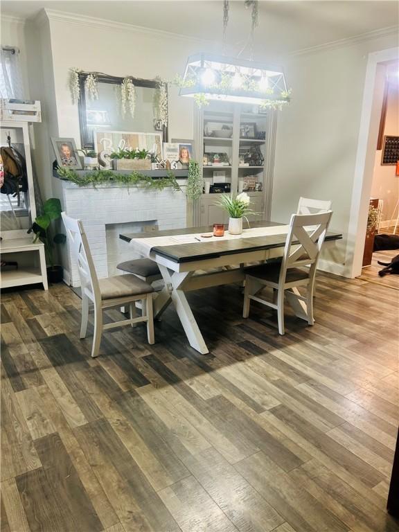 dining space featuring ornamental molding, an inviting chandelier, and wood finished floors