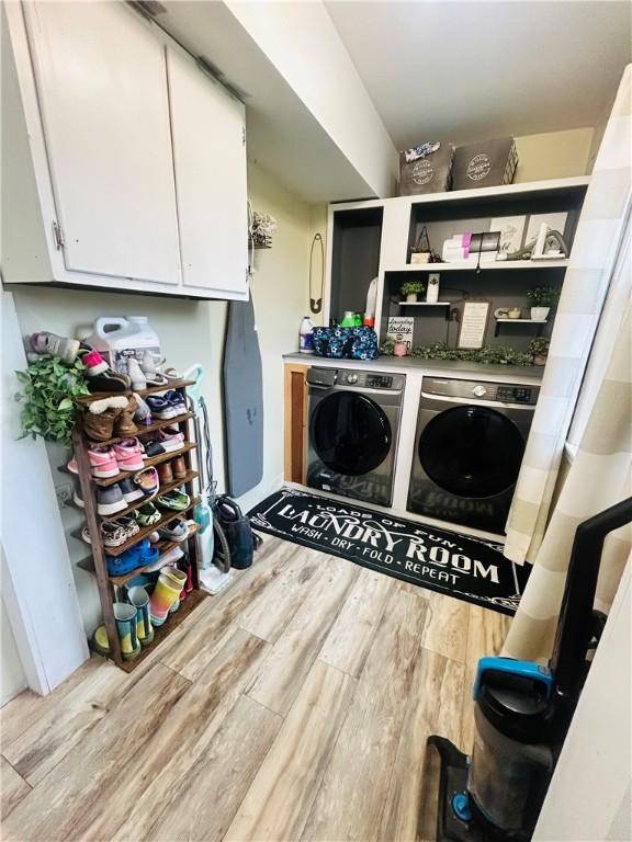washroom featuring wood finished floors, cabinet space, and washer and clothes dryer