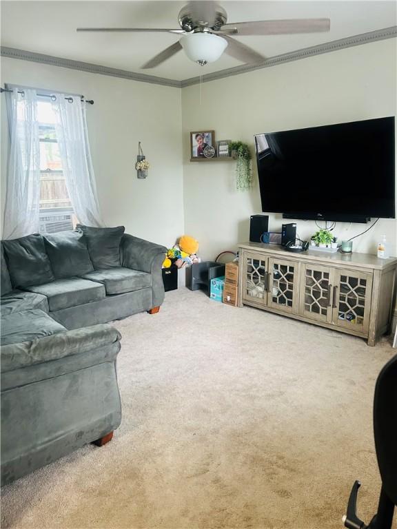 living area with ornamental molding, ceiling fan, and carpet