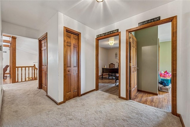 hall featuring an upstairs landing, carpet flooring, and baseboards