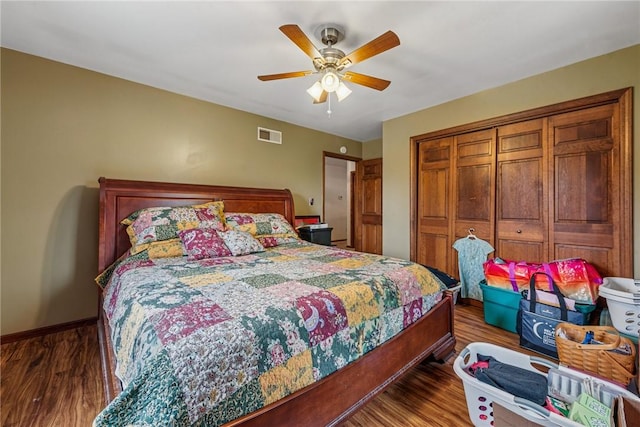 bedroom featuring a closet, dark wood-style flooring, baseboards, visible vents, and a ceiling fan