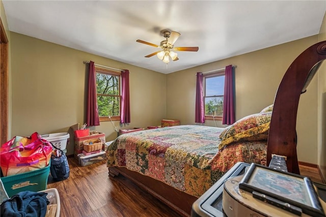 bedroom featuring wood finished floors, a ceiling fan, and multiple windows