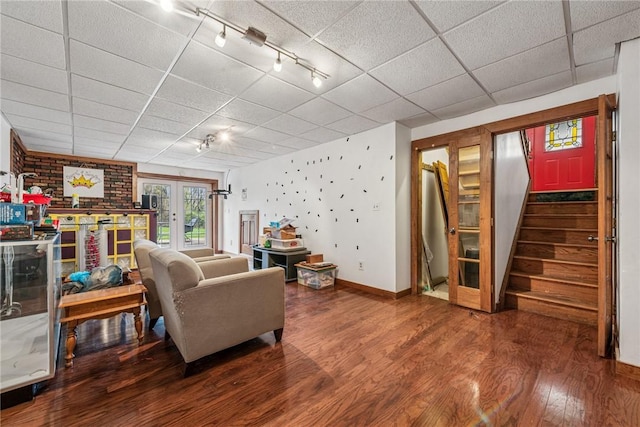 living area featuring french doors, baseboards, track lighting, wood finished floors, and stairs