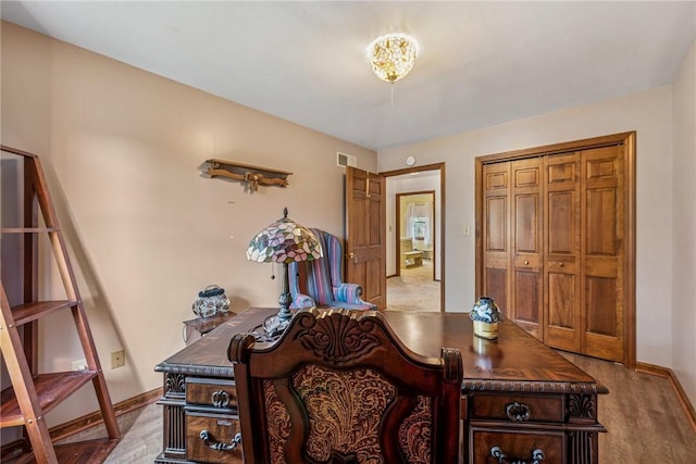 office space featuring baseboards, visible vents, and wood finished floors