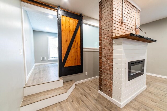 3052 Phelan Way, Polish Hill, PA 15219 - room details with wood finished floors, a barn door, a glass covered fireplace, and baseboards