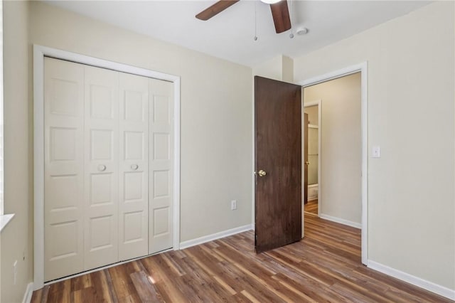 unfurnished bedroom featuring baseboards, ceiling fan, wood finished floors, and a closet
