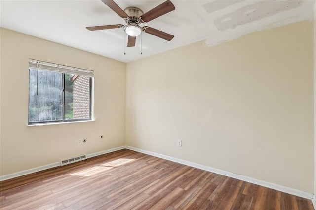 spare room featuring baseboards, a ceiling fan, wood finished floors, and visible vents