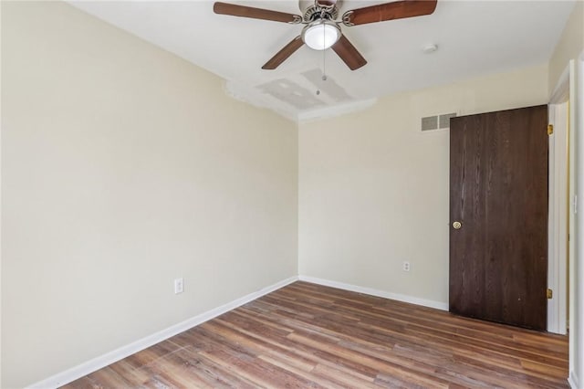 empty room featuring a ceiling fan, baseboards, visible vents, and wood finished floors