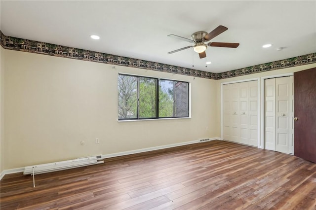 unfurnished bedroom with visible vents, multiple closets, wood finished floors, baseboards, and recessed lighting