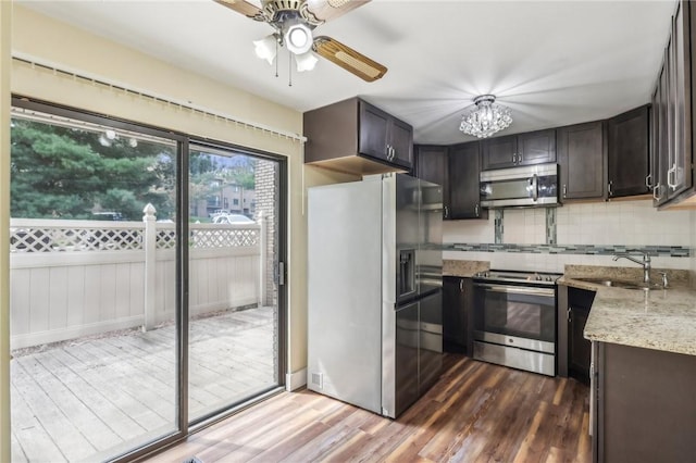 kitchen featuring ceiling fan with notable chandelier, decorative backsplash, stainless steel appliances, and dark wood-style flooring