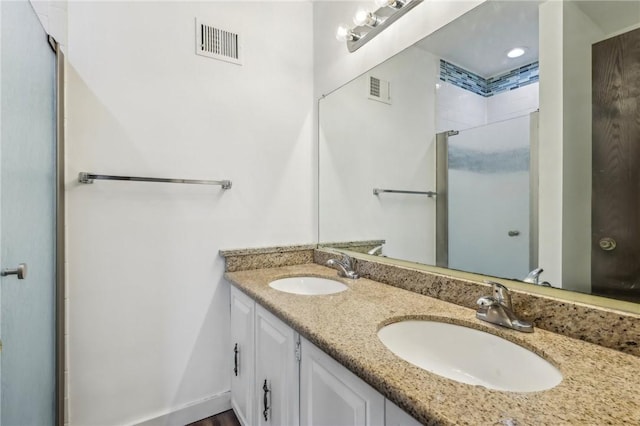 full bath with visible vents, a sink, an enclosed shower, and double vanity