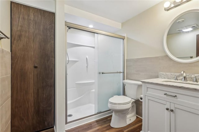 bathroom featuring tile walls, a stall shower, wood finished floors, vanity, and toilet