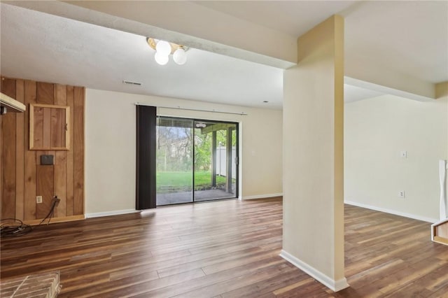 empty room featuring visible vents, baseboards, and wood finished floors