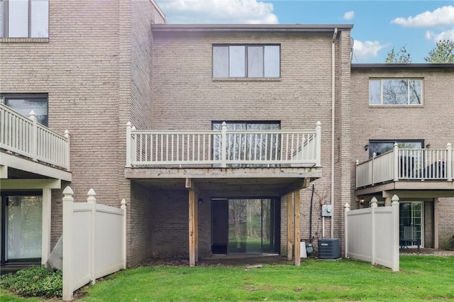 back of house with fence, a yard, and brick siding