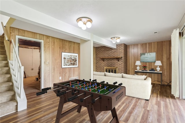 playroom with wooden walls, a fireplace, and wood finished floors