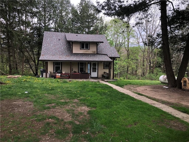 view of front of property with roof with shingles, a porch, and a front lawn