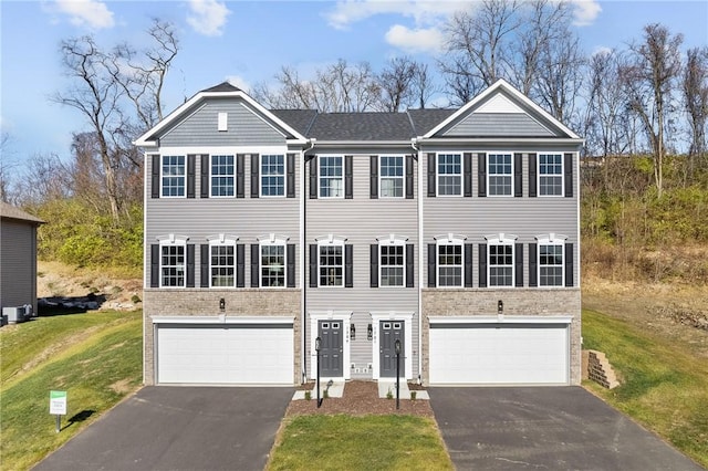 view of property with a garage, brick siding, a front lawn, and driveway