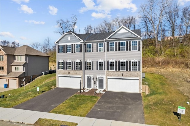 view of property with a front lawn, a garage, and aphalt driveway