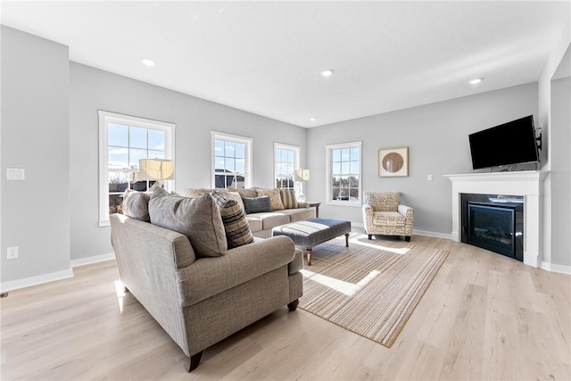 living room with light wood finished floors, baseboards, and a glass covered fireplace