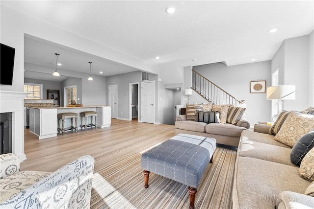living area featuring visible vents, light wood-type flooring, stairs, and recessed lighting