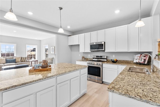 kitchen featuring light stone countertops, a sink, white cabinetry, and stainless steel appliances