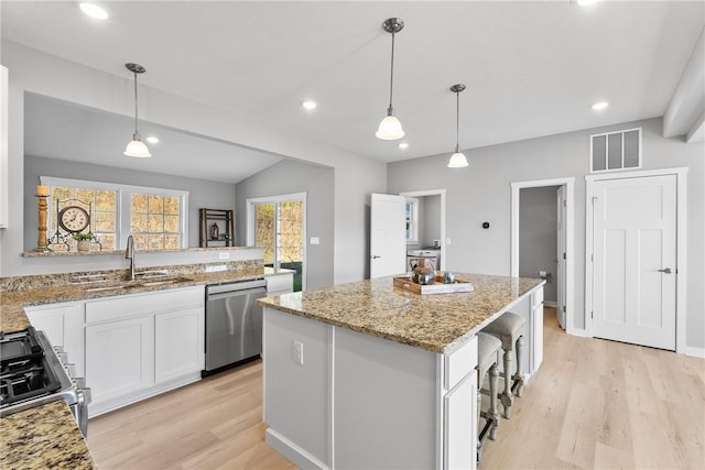 kitchen with light wood-style flooring, stainless steel appliances, a kitchen island, and a sink