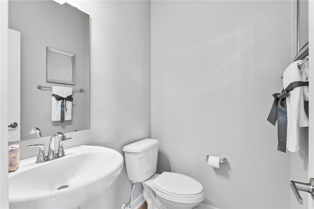 bathroom featuring toilet, a sink, and baseboards
