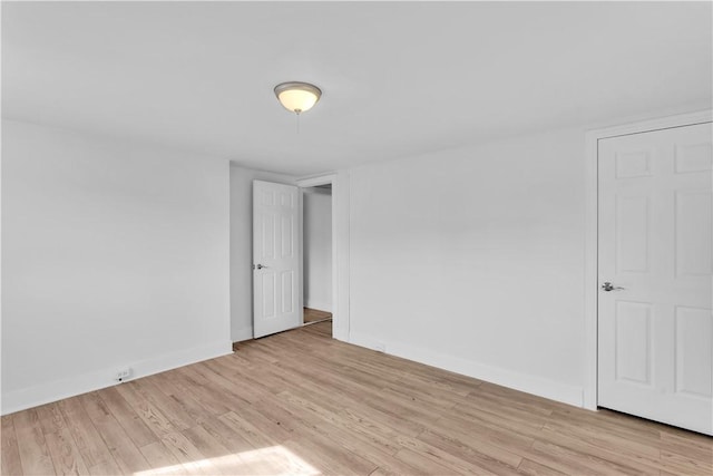unfurnished room with baseboards and light wood-style flooring