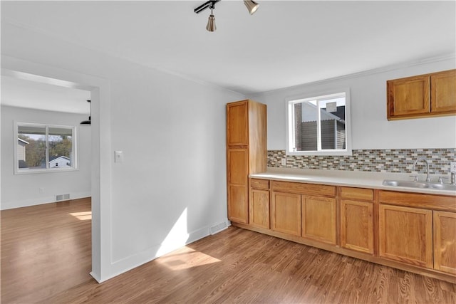 kitchen with visible vents, decorative backsplash, light wood-style flooring, and a sink
