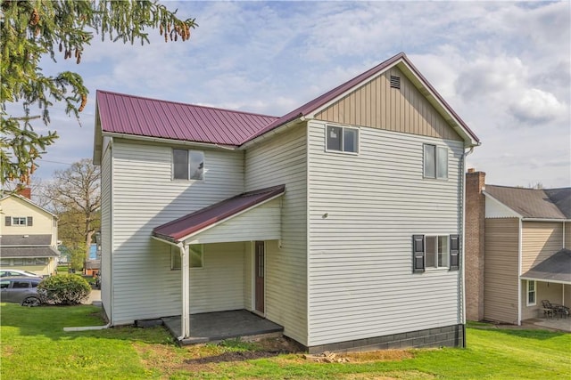back of house featuring metal roof and a lawn