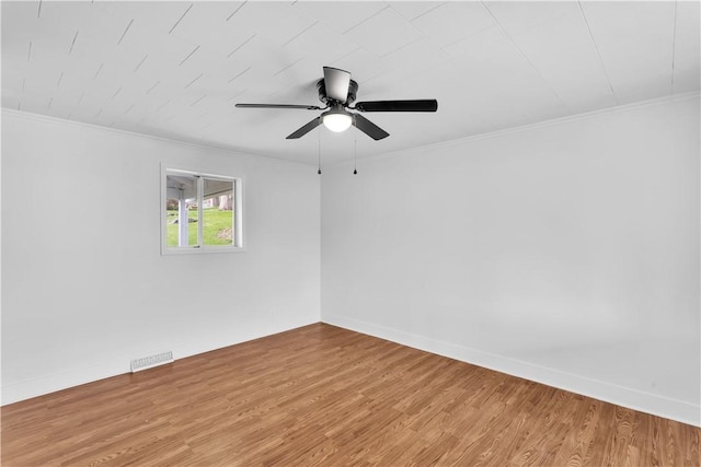 unfurnished room featuring ornamental molding, a ceiling fan, visible vents, and wood finished floors