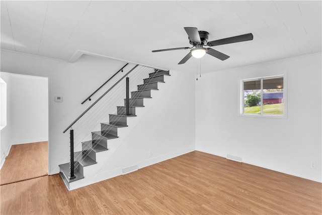 stairs with visible vents, wood finished floors, ceiling fan, and ornamental molding