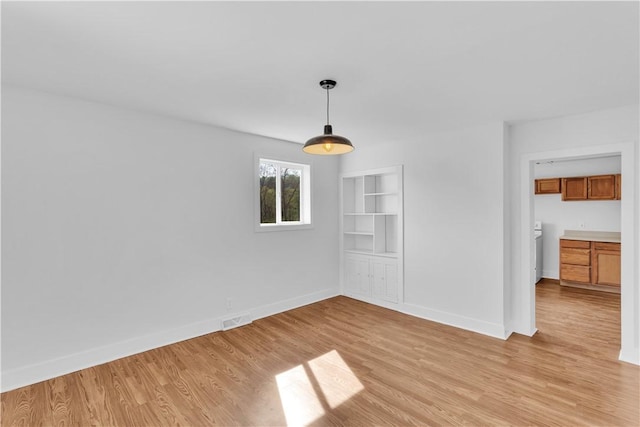 unfurnished dining area featuring baseboards, visible vents, and light wood-style floors