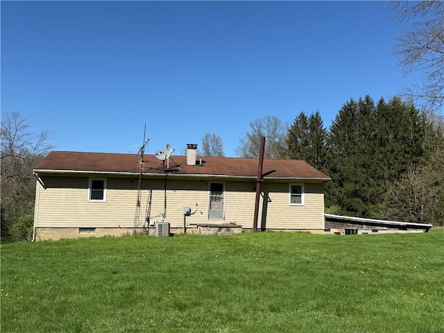 rear view of house with a yard, central AC, and a chimney
