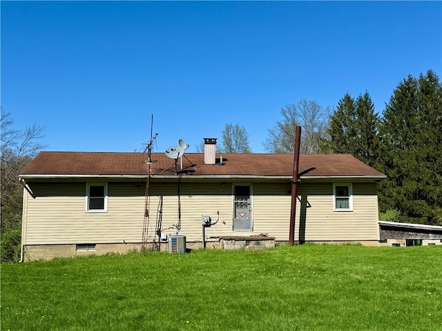 back of house with a chimney, a yard, and central AC unit