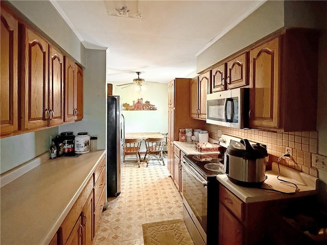 1025 S Lake Rd, Pa, PA 16137 - kitchen with appliances with stainless steel finishes, light floors, backsplash, brown cabinets, and a ceiling fan