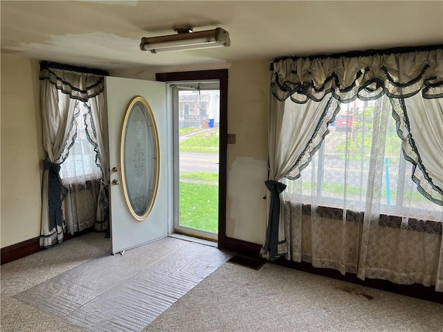 entrance foyer featuring baseboards, a healthy amount of sunlight, and carpet flooring