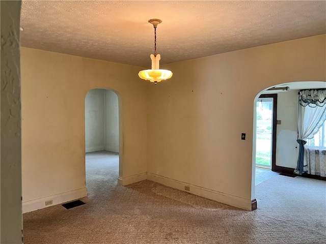 spare room with arched walkways, visible vents, carpet, and a textured ceiling