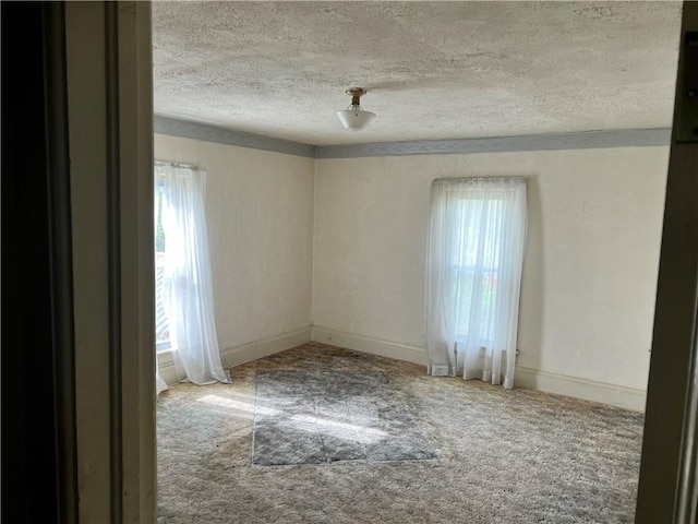 carpeted empty room featuring a textured ceiling