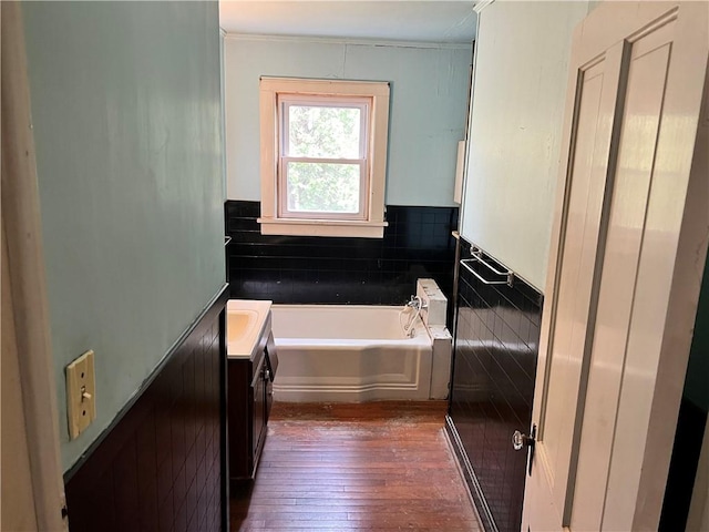 bathroom featuring a garden tub, vanity, hardwood / wood-style flooring, and crown molding