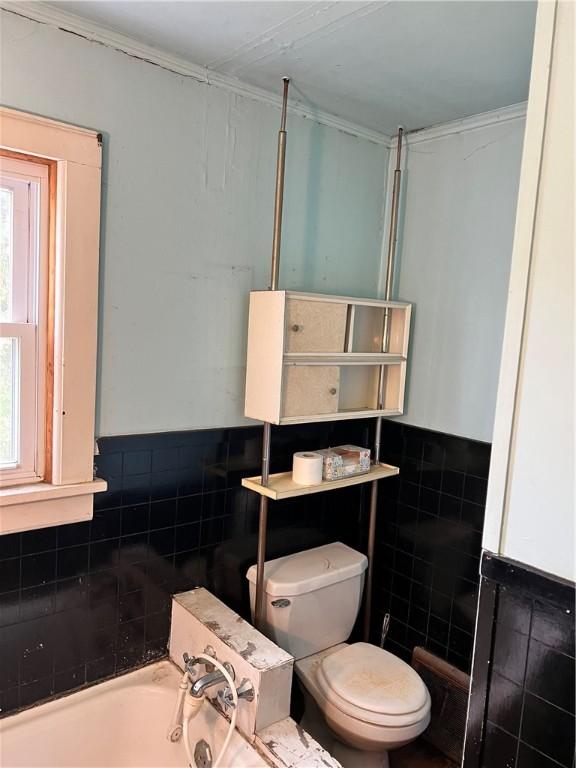 full bathroom featuring tile walls, toilet, a bathing tub, and plenty of natural light