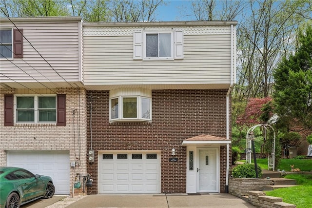 multi unit property featuring driveway, brick siding, and an attached garage