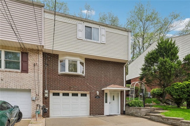 townhome / multi-family property featuring brick siding, driveway, and an attached garage