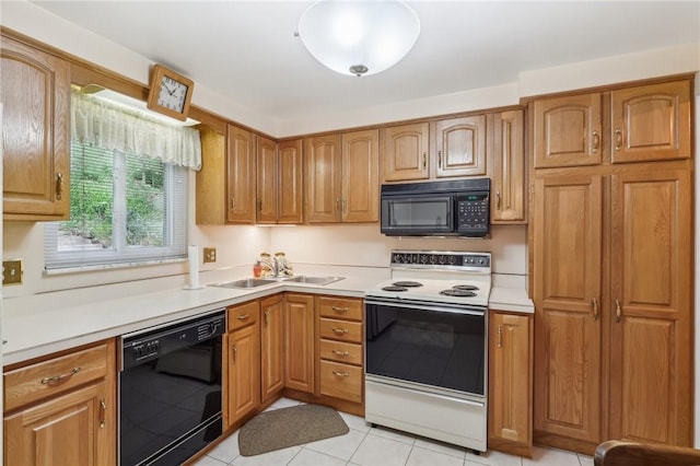 kitchen with brown cabinetry, light tile patterned floors, light countertops, black appliances, and a sink