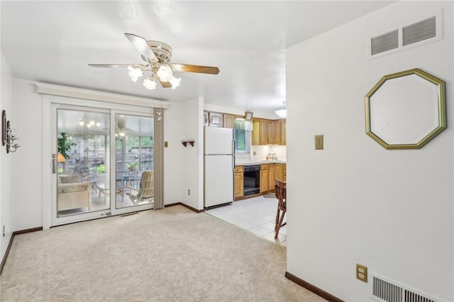 unfurnished living room with a ceiling fan, visible vents, light colored carpet, and baseboards