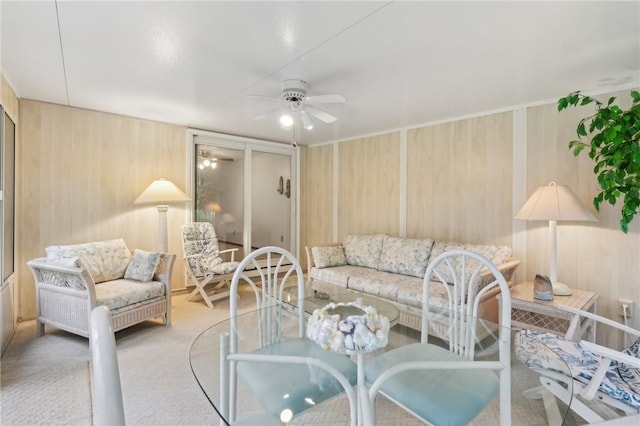 living room with wood walls, ceiling fan, and carpet flooring