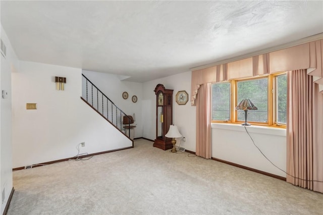 unfurnished living room with visible vents, baseboards, carpet flooring, and stairs
