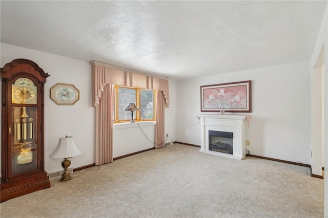 unfurnished living room with baseboards, carpet floors, and a glass covered fireplace