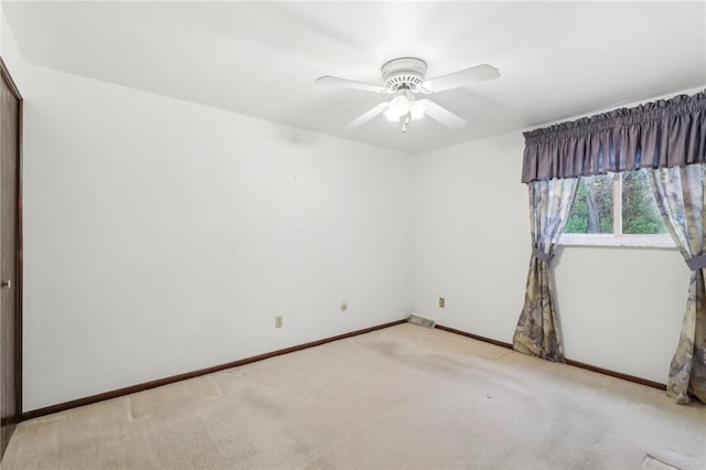spare room with light colored carpet, ceiling fan, and baseboards