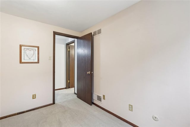 unfurnished room featuring baseboards, visible vents, and light carpet